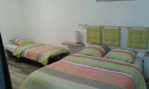 ラ・フロスリエールにあるGite Duguesclin VERTの緑色とカラフルなシーツが備わる客室のベッド2台