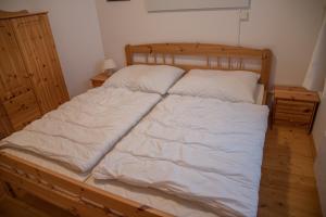 Elle comprend un grand lit avec des draps et des oreillers blancs. dans l'établissement Appartment Krassnig, à Turracher Höhe