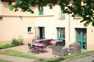 a patio with pink tables and chairs in front of a building at Hôtel Inn Design Resto Novo Châteaubriant in Châteaubriant