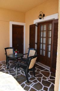a patio with two chairs and a table and a door at Eriketi Studios in Agia Marina Aegina