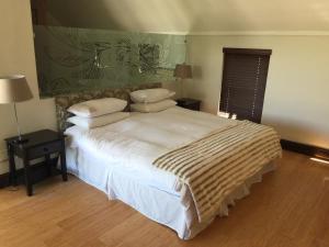 a bedroom with a bed with white sheets and pillows at De Zalze Luxury Lodge in Stellenbosch