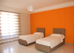プラーイア・ア・マーレにあるL'appartamentoのオレンジ色の壁の客室内のベッド2台