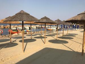 - un groupe de parasols en paille sur une plage dans l'établissement Leda House, à Villaggio del Fanciullo