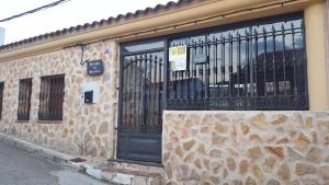 un edificio de piedra con una puerta negra y una valla en Rincon de Sandra, en Monteagudo de las Salinas