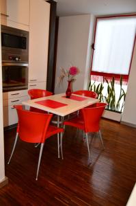 フンシャルにあるvista dos arrifesのダイニングルームテーブル(赤い椅子付)、花瓶
