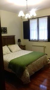 Un dormitorio con una cama con una manta verde. en Apartamentos Rurales Les Mestes, en Tazones