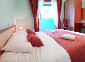 un grande letto con cuscini rossi e bianchi e una finestra di Guesthouse Pomena a Pomena