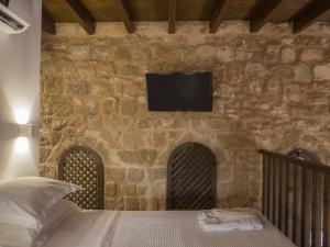 a bedroom with a bed with a tv on a stone wall at Trinity Boutique Hotel in Rhodes Town