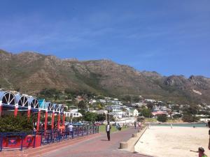 a beach with mountains in the background and people on the beach at Bergsig Selfcatering in Gordonʼs Bay