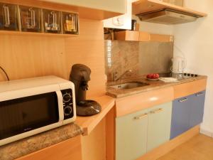 a small kitchen with a microwave and a sink at Les Pins . 2 p calme et terrasse in Nice