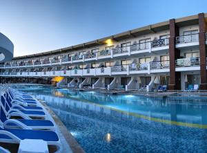 a hotel swimming pool with lounge chairs in front of a building at Ephesia Holiday Beach Club in Kuşadası