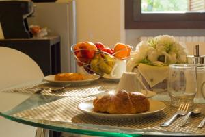 einen Tisch mit einem Teller Brot und einer Schale Obst in der Unterkunft B&B GARDA IN in Gardone Riviera
