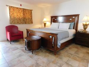 a bedroom with a large bed and a red chair at Drifter Motel in Silver City