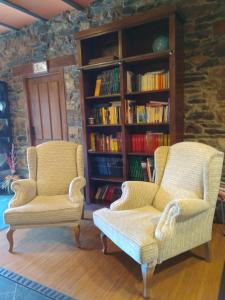 two chairs and a book shelf with books at Apartamentos Rurales Casa Cachon in Santa Eulalia de Cueras