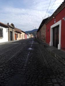 una calle adoquinada vacía en una ciudad con edificios en Casa De Leon, en Antigua Guatemala