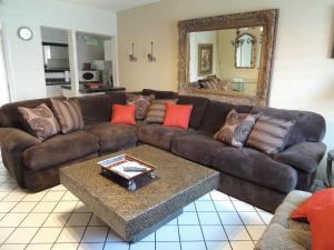 sala de estar con sofá marrón y espejo en Casa Larrea Inn en Palm Desert