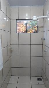 a bathroom with a glass shower with a window at Chácara Pousada Sagui in Cuiabá