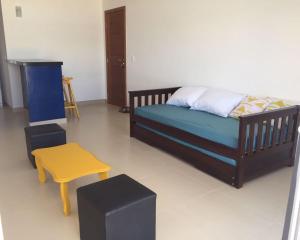 1 dormitorio con cama y taburete amarillo en Varandas da Praia Apartamentos, en Porto Seguro