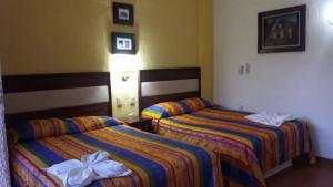 two beds in a hotel room next to each other at Real del Ambar in Tuxtla Gutiérrez