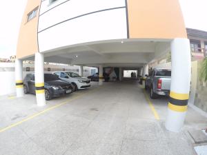 a parking lot with cars parked underneath a building at Brisa Brasil Residence in Fortaleza