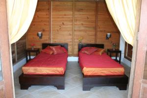 two beds in a room with wooden walls at Statia Lodge in Oranjestad