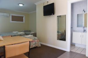 Zimmer mit einem Tisch und einem TV an der Wand in der Unterkunft Mia Motel in Griffith