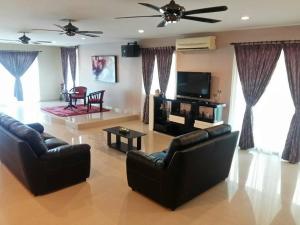 uma sala de estar com 2 sofás e uma televisão de ecrã plano em Port Dickson Holiday Home Villa em Port Dickson