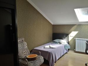 een slaapkamer met een bed en een stoel bij Anasera in Tbilisi City