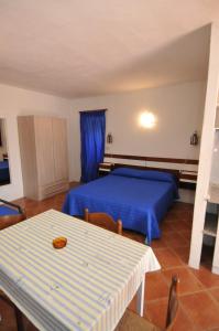 a bedroom with a blue bed and a table at Appartamenti I Lauri in Porto Azzurro