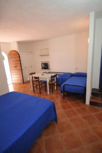 a room with two beds and a table and chairs at Appartamenti I Lauri in Porto Azzurro
