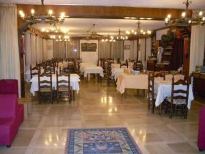 uma sala de jantar com mesas brancas, cadeiras e luzes em Dujany em Nus