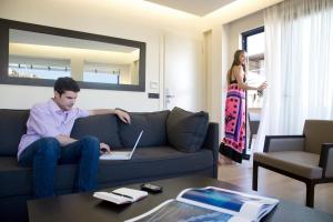 a man sitting on a couch with a laptop in a living room at O&B Athens Boutique Hotel in Athens