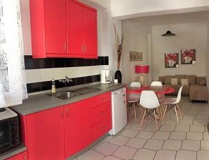 アカラヴィにあるPhilippos Apartmentsのキッチン(赤いキャビネット、テーブル、椅子付)