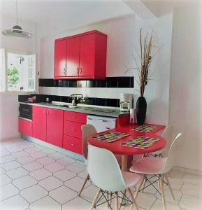 アカラヴィにあるPhilippos Apartmentsの赤いキャビネット、赤いテーブルと椅子付きのキッチン