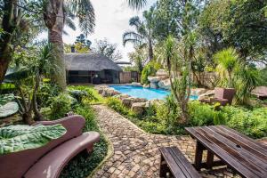 a garden with a bench and a swimming pool at Summer Garden Guest House (The Palms) in Benoni