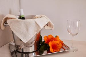 una licuadora con flores naranjas y una copa de vino en Alba D'Amore Hotel & Spa en Lampedusa