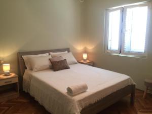 1 dormitorio con 1 cama con 2 lámparas y una ventana en Apartmani Suric en Privlaka
