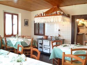 a dining room with two tables and a kitchen at Agriturismo Fogolar da Capo in Orzano