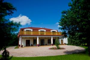 una gran casa blanca con techo rojo en Miodowy Zakątek Całoroczne domki i pokoje przy Suntago, Deepspot, en Mszczonów