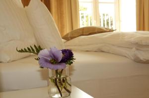 eine Vase mit lila Blumen auf einem Tisch neben einem Bett in der Unterkunft Domizil Gols, Boutique - Hotel in Gols