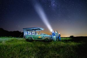 a group of people standing next to a green jeep under the stars at St Lucia Eco Lodge in St Lucia