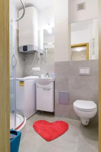 baño con aseo y alfombra roja para el corazón en Plac Wielkopolski Apartment en Poznan