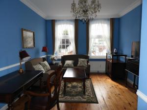 a living room with blue walls and a table and chairs at Hotel Villa Schneverdingen in Schneverdingen