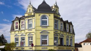 ein gelbes Gebäude mit einem Turm darüber in der Unterkunft Hotel Villa Schneverdingen in Schneverdingen