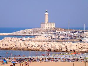 a group of people on a beach with a lighthouse at Hotel Yria in Vieste