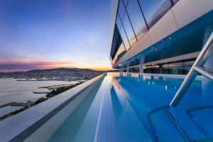 a swimming pool on the roof of a building with a sunset at Hotel Olympia Sky in Vodice