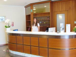 a woman standing at a counter in a library at Hotel Stella Maris in Grado