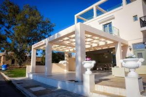 a white house with a pergola and two white vases at Costa Rampane in Plitra