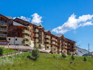 a large apartment building on a hill with mountains in the background at Résidence Les Toits du Dévoluy in Le Dévoluy
