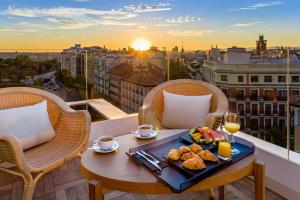 a table with food and drinks on a balcony with a view at H10 Puerta de Alcalá in Madrid